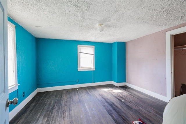 unfurnished bedroom with a textured ceiling, baseboards, and wood finished floors