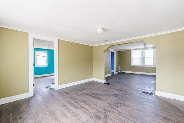 spare room with visible vents, arched walkways, baseboards, and wood finished floors