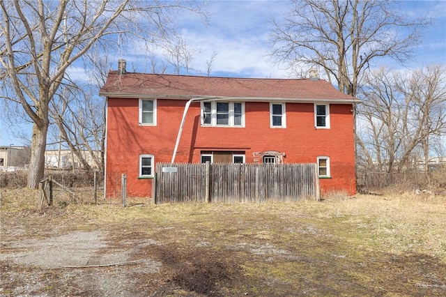 view of home's exterior featuring brick siding, driveway, and fence