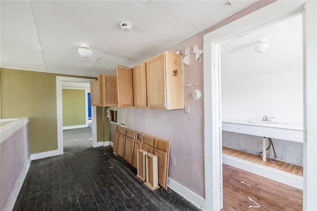 hall featuring baseboards, dark wood-style flooring, and a sink