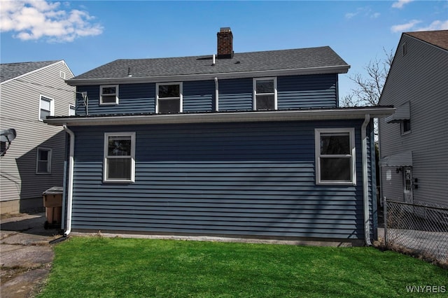 rear view of house featuring a yard, a chimney, and fence