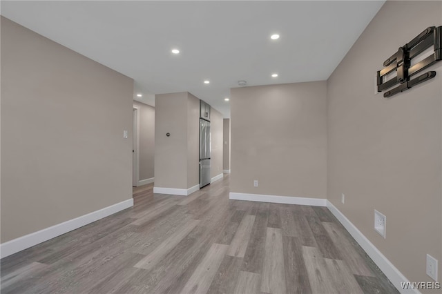 unfurnished room featuring recessed lighting, light wood-style flooring, and baseboards