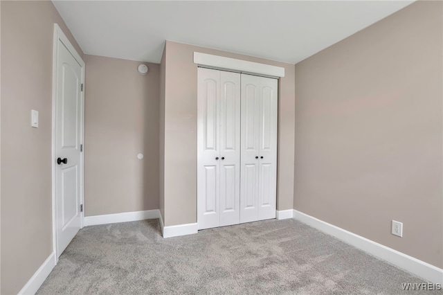 unfurnished bedroom with a closet, carpet flooring, and baseboards