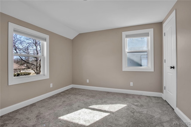 empty room featuring vaulted ceiling, baseboards, and carpet floors