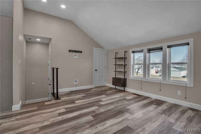 unfurnished living room featuring recessed lighting, baseboards, lofted ceiling, and wood finished floors