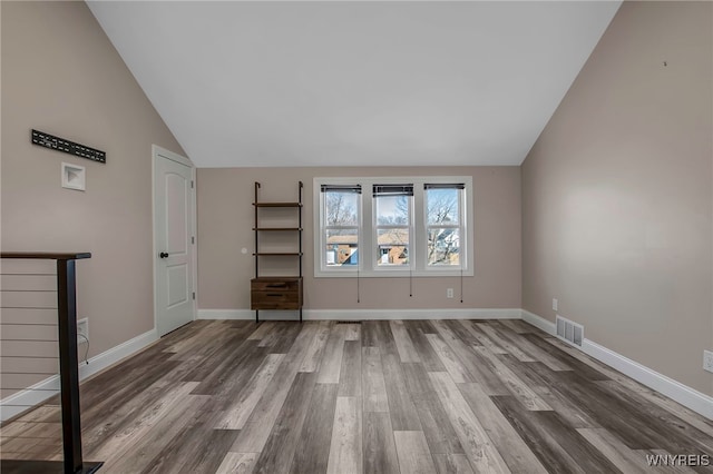 empty room with visible vents, high vaulted ceiling, baseboards, and wood finished floors