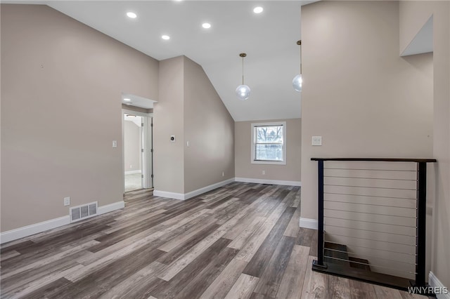 unfurnished living room with wood finished floors, visible vents, baseboards, lofted ceiling, and recessed lighting