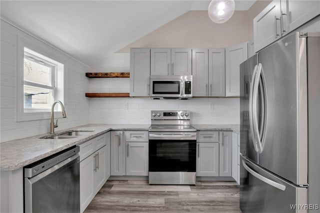 kitchen featuring a sink, backsplash, vaulted ceiling, stainless steel appliances, and open shelves