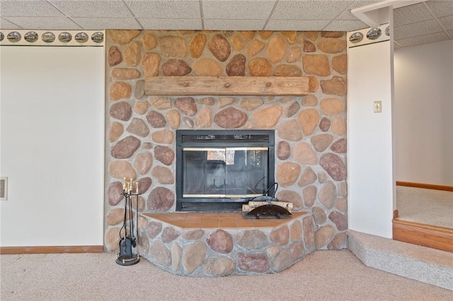 interior details featuring carpet flooring, a fireplace, baseboards, and a drop ceiling