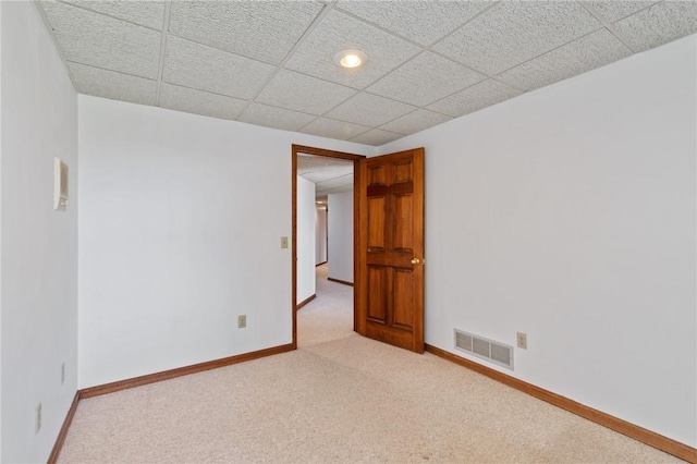 carpeted spare room with a paneled ceiling, visible vents, and baseboards