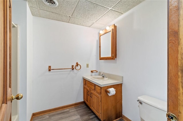 bathroom featuring wood finished floors, visible vents, baseboards, a paneled ceiling, and toilet