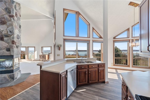 kitchen featuring open floor plan, light countertops, dark wood-style flooring, stainless steel dishwasher, and a sink