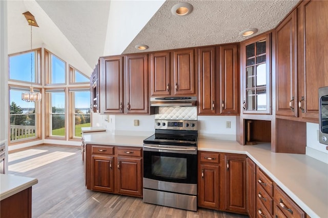 kitchen featuring light wood finished floors, lofted ceiling, stainless steel electric range, light countertops, and under cabinet range hood