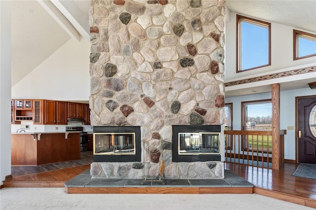 living room featuring wood finished floors, a high ceiling, a fireplace, and baseboards