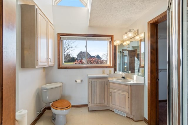 bathroom featuring vanity, baseboards, visible vents, a textured ceiling, and toilet