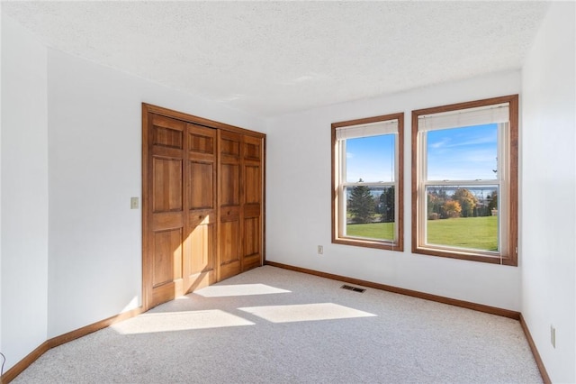 unfurnished bedroom with light colored carpet, visible vents, and a textured ceiling