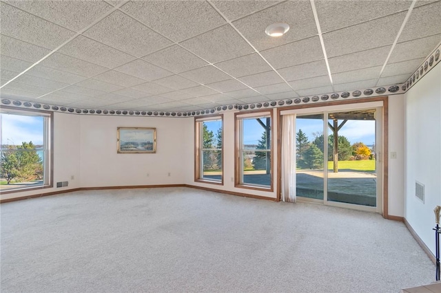 carpeted spare room with plenty of natural light, a paneled ceiling, and baseboards