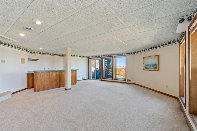 spare room with baseboards, light colored carpet, and a dry bar