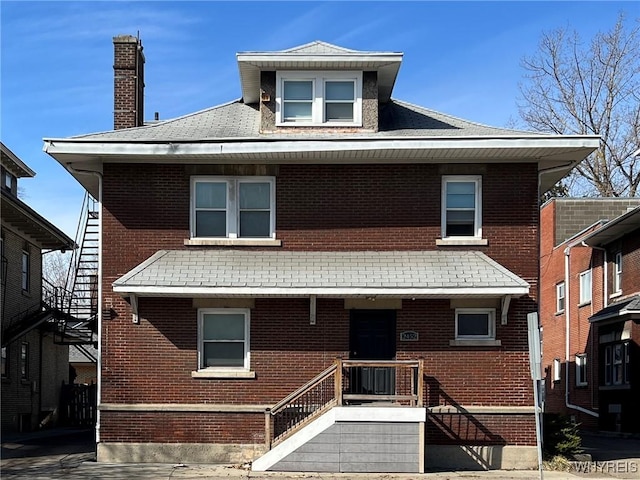 american foursquare style home featuring brick siding, covered porch, and a chimney