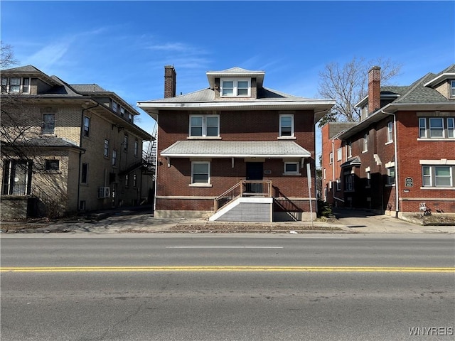 american foursquare style home featuring brick siding and a chimney