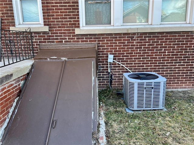 exterior details with a bulkhead entry, brick siding, and central AC