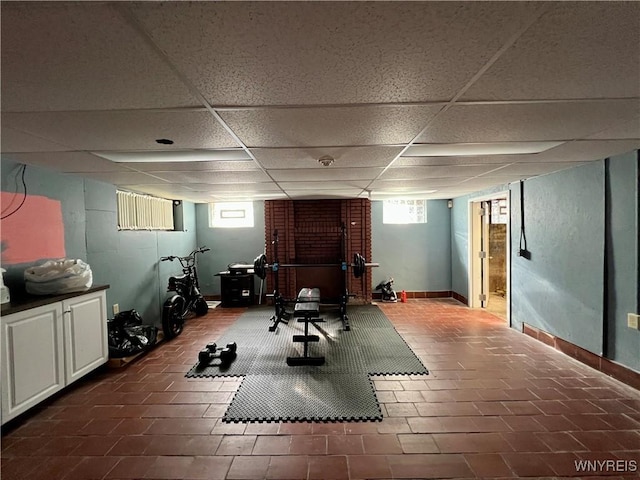 workout room with plenty of natural light, a paneled ceiling, and baseboards