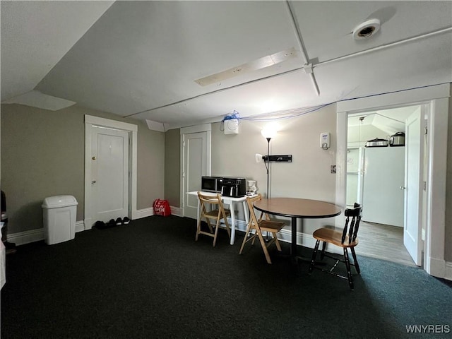 dining area featuring lofted ceiling, baseboards, and dark colored carpet