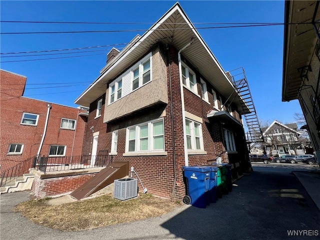 view of side of property with central AC unit and brick siding