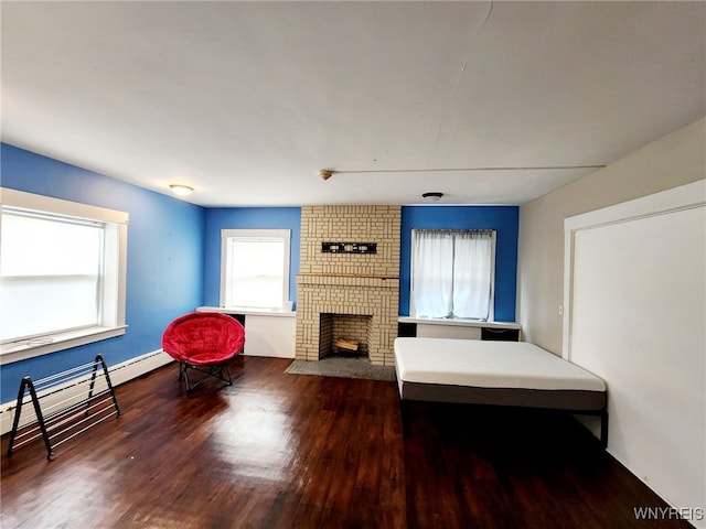 living area featuring a baseboard heating unit, a brick fireplace, and wood finished floors