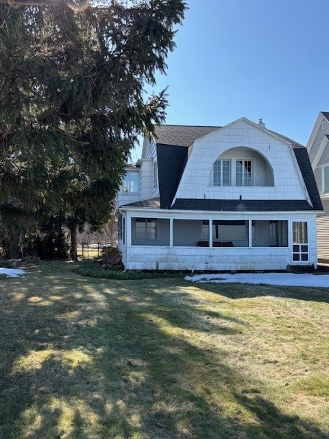 exterior space with a front lawn, a gambrel roof, a sunroom, and roof with shingles