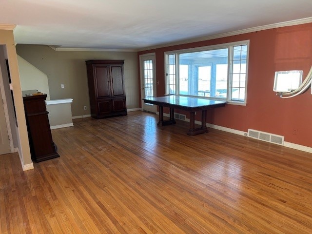 unfurnished dining area featuring visible vents, baseboards, crown molding, and light wood finished floors