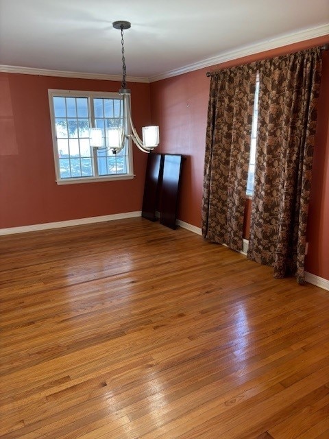 unfurnished dining area with wood finished floors, baseboards, and ornamental molding