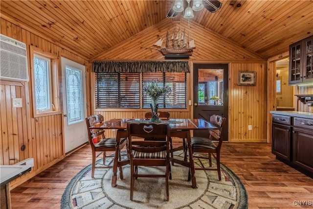 dining area featuring vaulted ceiling, wood finished floors, wood walls, and wooden ceiling