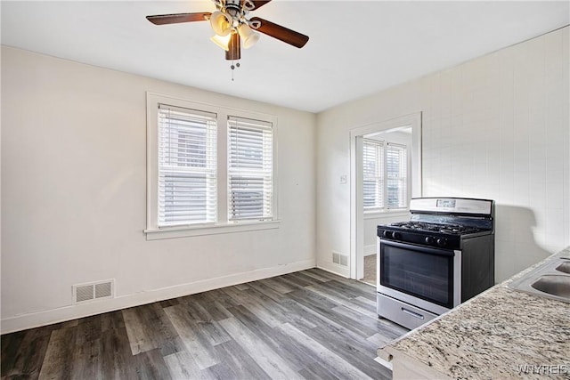 kitchen featuring visible vents, stainless steel gas stove, baseboards, and wood finished floors