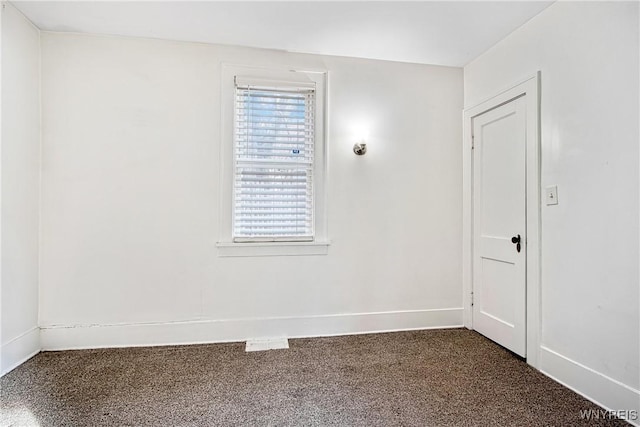 spare room featuring dark carpet and baseboards