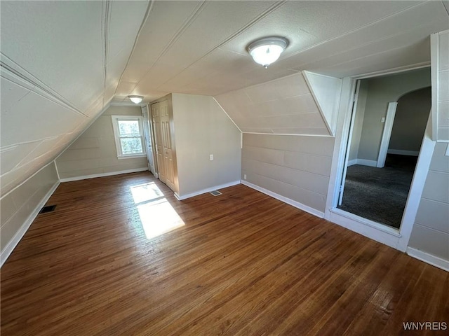 additional living space with vaulted ceiling, wood finished floors, and visible vents
