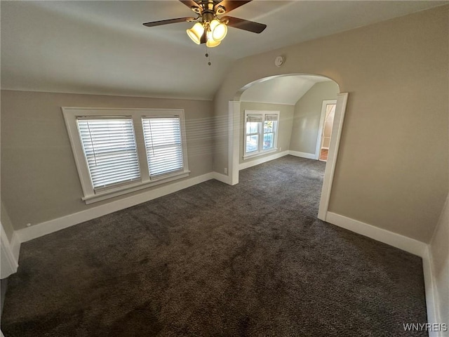 spare room with ceiling fan, baseboards, lofted ceiling, and dark colored carpet