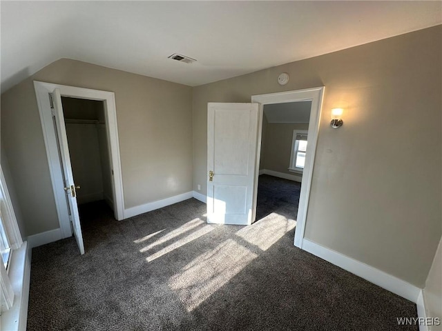 unfurnished bedroom with lofted ceiling, baseboards, visible vents, and dark colored carpet