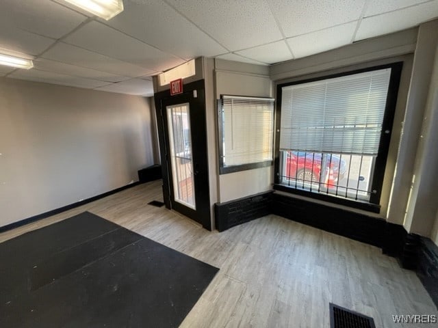 empty room featuring visible vents, wood finished floors, baseboards, and a drop ceiling