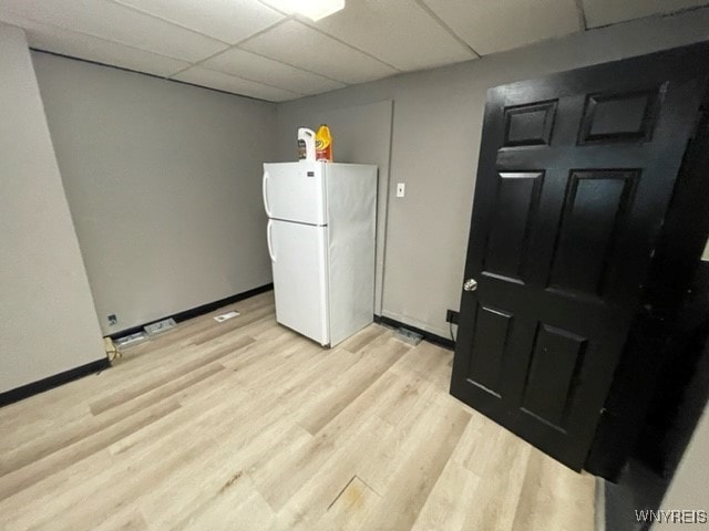 interior space with baseboards, a paneled ceiling, and light wood-style floors