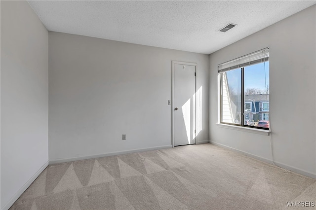 empty room with visible vents, carpet floors, a textured ceiling, and baseboards