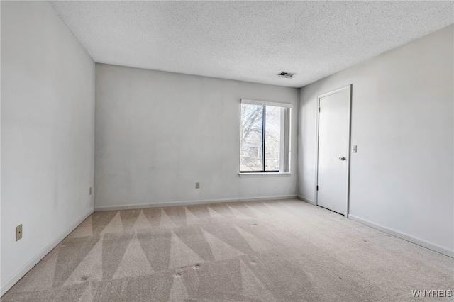 carpeted spare room with visible vents, baseboards, and a textured ceiling