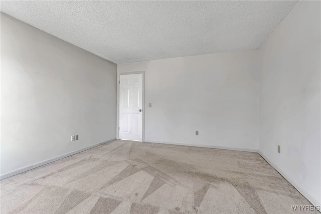 empty room with baseboards, carpet, and a textured ceiling