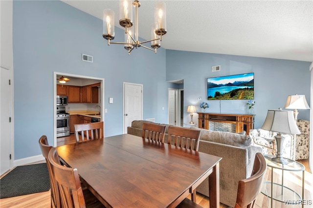 dining space featuring light wood finished floors, visible vents, a notable chandelier, and vaulted ceiling