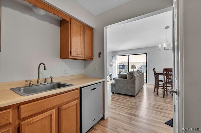 kitchen with light wood-type flooring, a sink, open floor plan, light countertops, and dishwashing machine