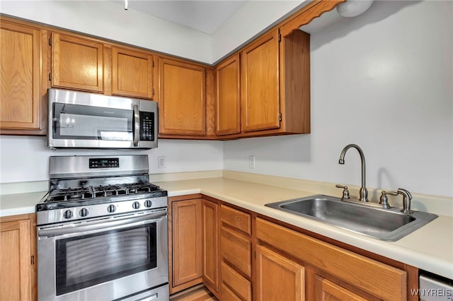 kitchen featuring brown cabinets, stainless steel appliances, light countertops, and a sink