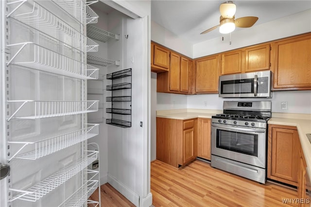 kitchen featuring light countertops, brown cabinetry, light wood-type flooring, and stainless steel appliances