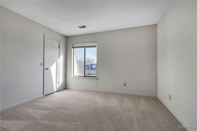 carpeted spare room with visible vents, a textured ceiling, and baseboards