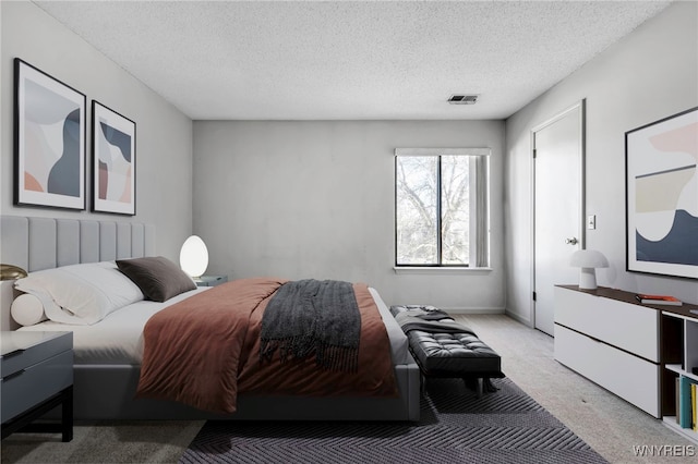 bedroom featuring visible vents, light carpet, and a textured ceiling