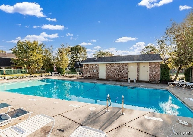 pool with a patio area and fence